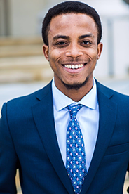 John Ampiah-Addison in dark blue suite with blue shirt and patterned tie.