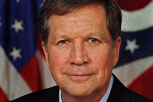 Man with brown hair in front of American flag.