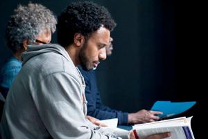 Professor reading a book, wearing a grey sweatshirt.