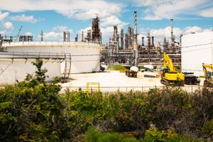 Trees and shrubs in front of industrial site of an oil refinery.