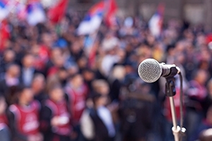 A blurred out crowd behind a foreground microphone.