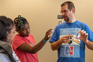 Aaron Grocholski shows visiting students the effects of polarizing filters