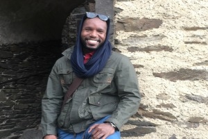 Russell Cox stands outside against a stone wall.