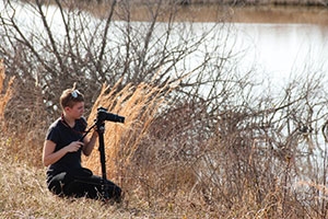 Woman with video camera on bank of bay