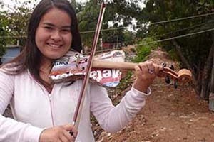 Girl holding violin made of recycled garbage