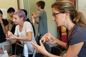 Two graduate students hold up diagrams of brains to middle school students