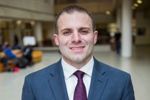 Sam wearing a blue suit and red tie in a well-lit room