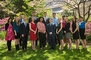 Student award winners gather in the amphitheater grass and shade.