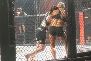 Two women MMA fighters in a cage match.