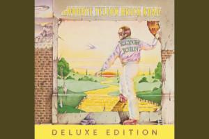 Album art from Elton John album Goodbye Yellow Brick Road. Man walking through a brick doorway onto the yellow brick road from Wizard of Oz.