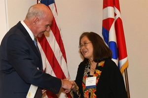 Provost shakes professor's hand, holding a piece of paper in the other hand