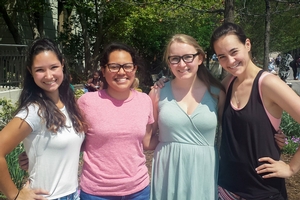 4 smiling people in casual clothing stand in a line in the sun