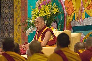 The Dalai Lama in front of a painted religious banner conducts a teaching at American University