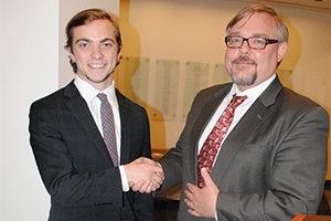 A man gives Matt Mullin an award and shakes his hand.