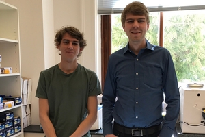 Two young men stand in an office. One is considerably taller
