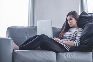 student working from home with laptop on the couch