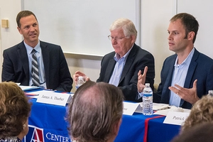 Three men seated at panel discussion.