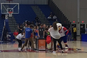 Fans in Bender Arena gather around recycling bins, with Clawed joining in