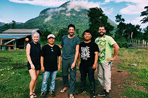 Mcgoff with production team in Laos, posing in front of a mountain Mcgoff with production team in Laos, posing in front of a mountain