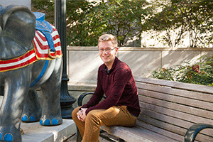 Harrison sitting in front of Kerwin Hall near the elephant